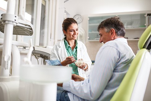 Dentist smiling while talking to patient in treatment chair