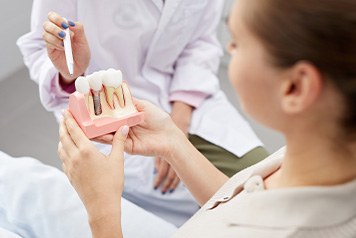 Dentist pointing to model of dental implant