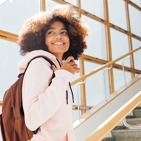 Teen smiling while walking up stairs at school