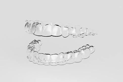 Clear aligners over off-white background that are difficult to see